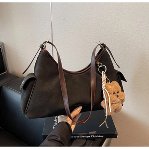 Dettaglio borsa hobo in pelle scamosciata con spalline in pelle e un ciondolo orso di peluche