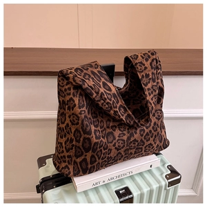 Detail of vintage leopard print tote bag placed on a green suitcase for travel styling