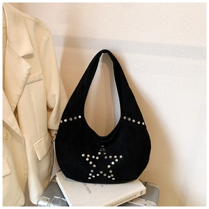 Detail of black suede hobo bag with silver star-shaped rivets on a vintage suitcase