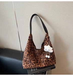 Detail of leopard print suede hobo bag with a plush cloud charm and black leather strap