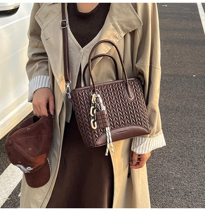 Close-up of retro dark brown pleated tote bag with woven texture and decorative charms