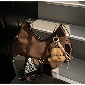 Dettaglio borsa a tracolla vintage marrone con ciondolo a cucciolo e nappine intrecciate