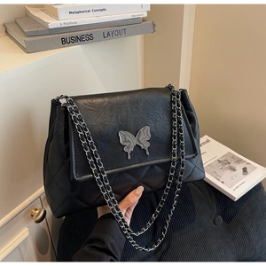 Détail du sac matelassé noir avec fermoir papillon argenté et bandoulière en chaîne