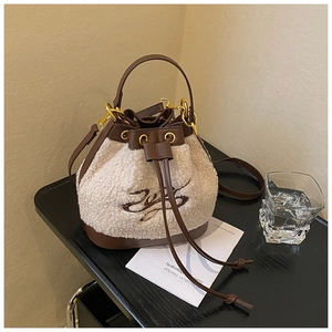 Detail of plush beige sherpa bucket bag with brown leather trim and drawstring closure
