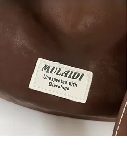 Detailed close-up of dark brown leather texture with white fabric stitched brand label