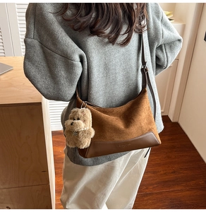 Detail of suede crossbody bag with teddy charm and adjustable leather shoulder strap