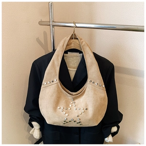 Detailed close-up of khaki suede hobo bag with silver star-shaped metal rivets