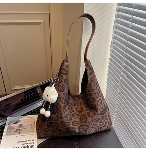 Brown leopard print suede tote bag with plush cloud charm on a minimalist desk