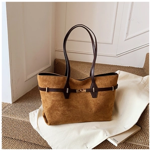Close-up of brown suede tote bag with leather handles and a vintage gold lock detail