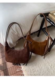 Minimalist hobo bags in dark coffee and caramel suede displayed in a cozy bedroom setting