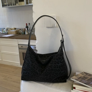 Detail of black leopard print hobo bag featuring adjustable leather strap and matte texture