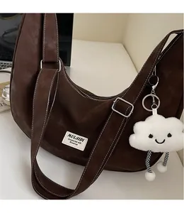 Detail view of large dark brown crescent bag with white plush cloud charm and strap