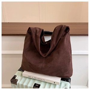 Detail of dark brown faux suede tote bag with vertical stitching on a suitcase