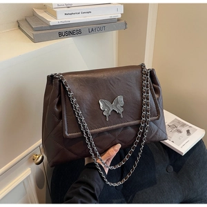 Détail de la boucle papillon en métal marbré argenté sur le sac matelassé marron foncé
