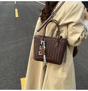 Detail of dark brown woven textured bucket bag with chocolate charm and crossbody strap