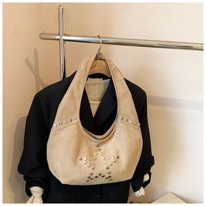 Detail of silver rivets star pattern on beige suede leather underarm shoulder bag
