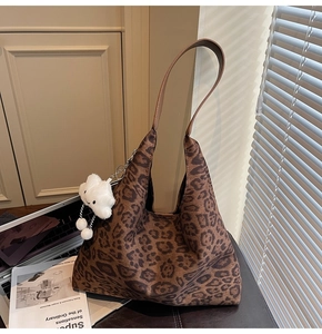 Detail of leopard print suede tote bag featuring a fluffy white cloud charm on the strap