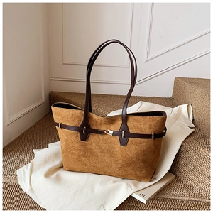 Detail of vintage brown suede tote bag featuring premium leather straps and buckle decor