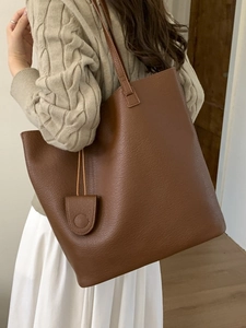 Brown faux leather tote bag for women with matching charm pendant worn by model