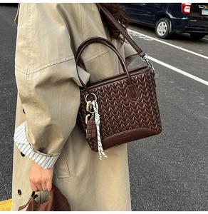 Detail of deep brown woven bucket bag featuring chic chocolate charm and leather textures