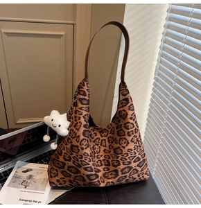 Close-up of leopard print suede hobo bag with plush cloud charm and leather strap
