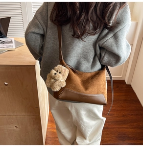 Detail of suede shoulder bag featuring a cute plush dog pendant and fashion brand logo