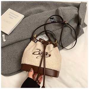 Detailed view of winter bucket bag showing sherpa texture, leather trim and metal feet