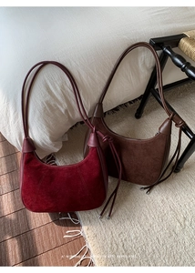 Detail view of burgundy and brown suede crescent bags with retro tassel knot decoration