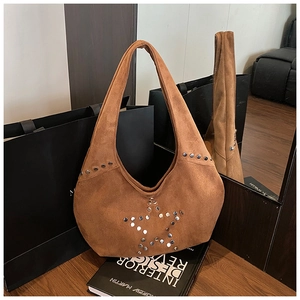 Detail of silver rivets star pattern on brown suede leather minimalist hobo shoulder bag