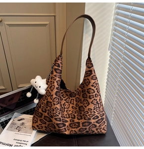 Detail of leopard print suede shoulder bag with brown strap and cloud charm accessory