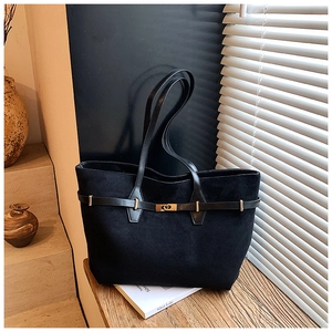 Detail of a black large tote bag with gold lock hardware and premium matte texture