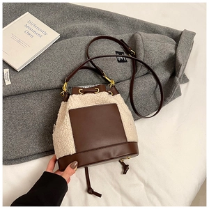 Detail of winter bucket bag made of cream fleece and dark brown leather stitching