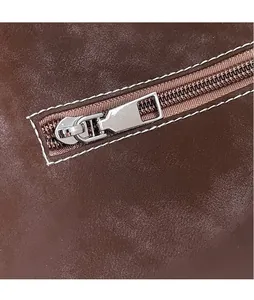 Detailed macro shot of silver metal zipper and white stitching on dark brown leather bag