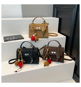 Close-up of suede retro Kelly bags in khaki, black and brown with ethnic tassel charms