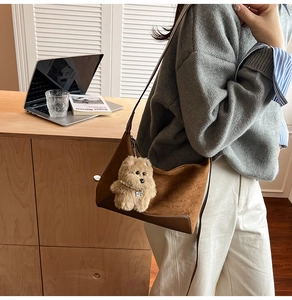 Detail of suede shoulder bag with brown leather trim and cute plush puppy charm