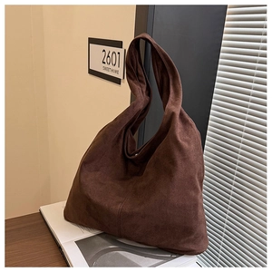 Detail of dark brown faux suede tote bag with vertical stitching on wooden table