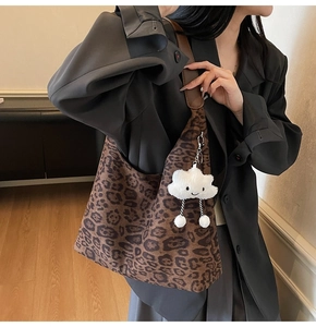 Close-up of vintage brown leopard print suede tote bag with a white plush cloud charm