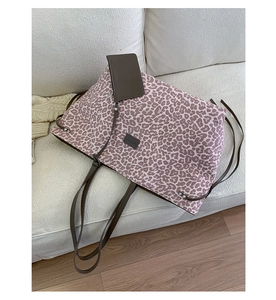 Détail du sac cabas imprimé léopard avec anses en cuir marron et petit pendentif décoratif