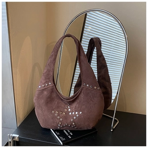 Close-up of silver studs forming a star pattern on a dark brown suede tote bag