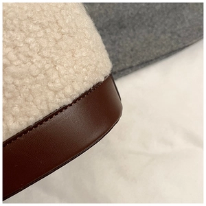 Detailed close-up of white sherpa fabric and dark brown leather stitching on a handbag