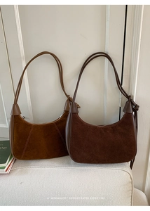 Close-up of retro suede crescent bags showing smooth leather trim and metal zipper