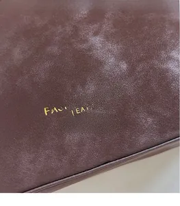 Close-up of golden embossed text on premium dark brown leather of the bucket bag