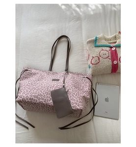 Sac fourre-tout rose imprimé léopard avec pochette assortie et un iPad sur un lit