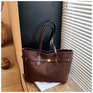 Detailed macro view of dark brown suede tote bag with metallic twist lock and belt detail