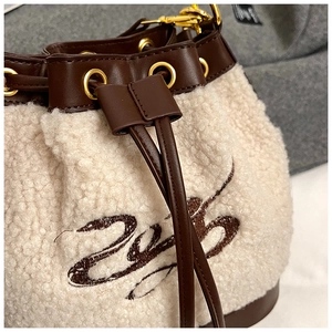 Detail of faux shearling bucket bag with brown embroidery and leather drawstring