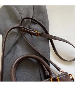 Detail view of dark brown matte leather bucket bag with adjustable strap and gold hardware