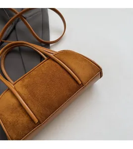 Detail of brown suede and leather stitching on a vintage Boston-style crossbody bag