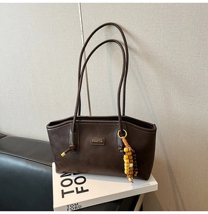 Detail of dark brown tote bag with lychee texture and colorful wood bead charm