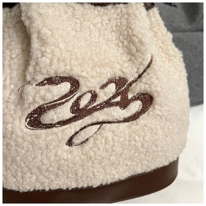 Detail of soft cream faux fur texture with 2024 art lettering and brown leather base