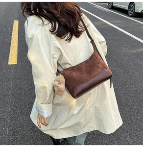 Detailed view of deep brown vintage shoulder bag with plush pendant and faux suede texture